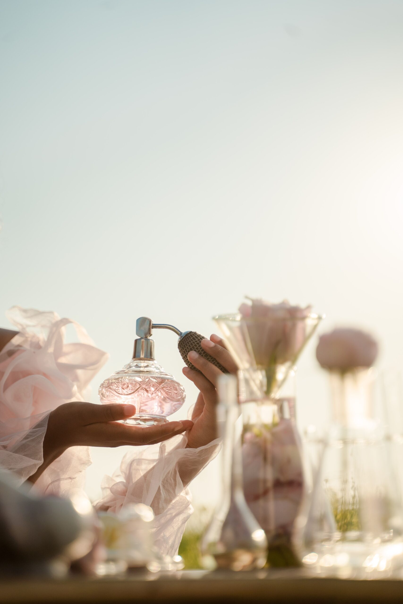 Hand holding a cut-glass perfume atomizer catching sunlight